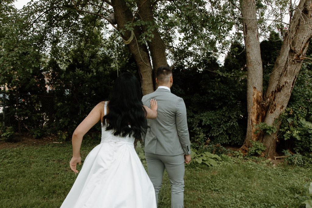 Bride tapping groom on shoulder for backyard wedding first look