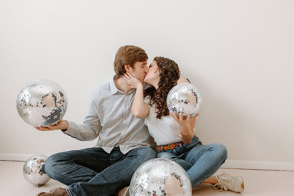 Couple kiss while holding disco balls during studio session