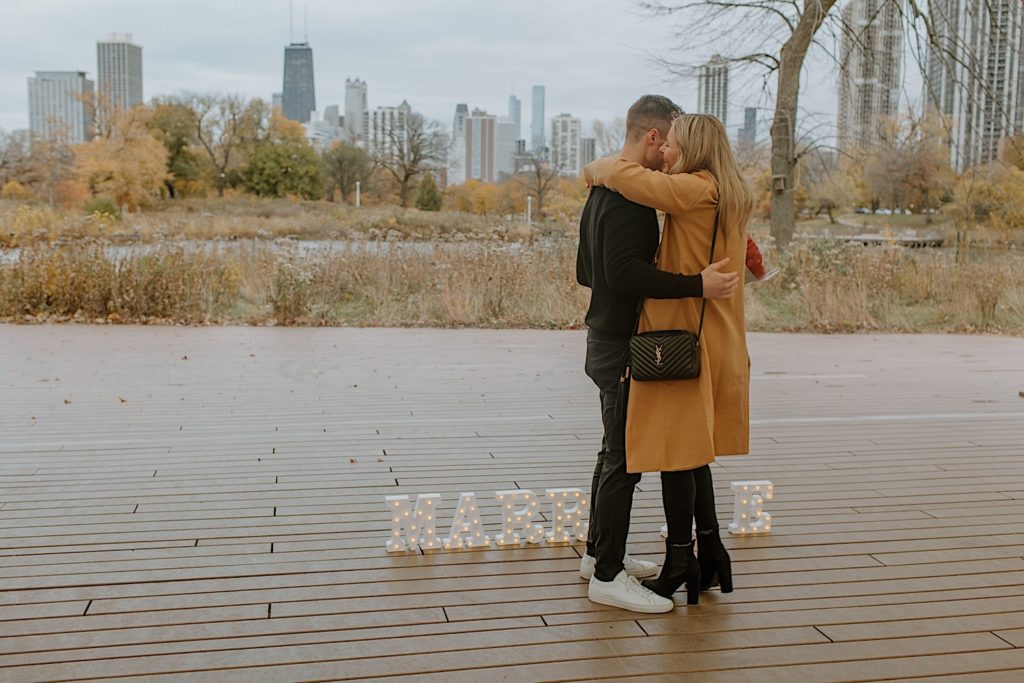 Couple hugs at perfectly planned proposal